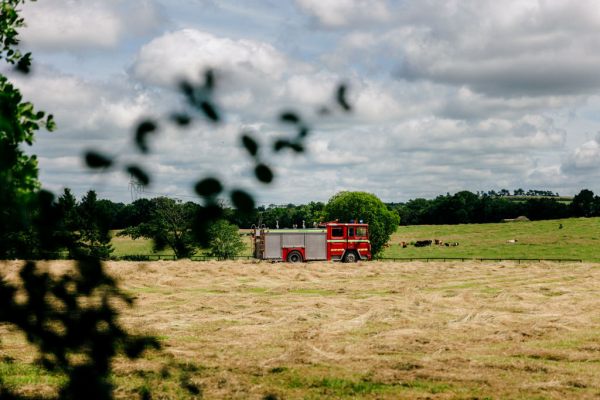 firetruck with bride in passenger seat arrives passing farm land