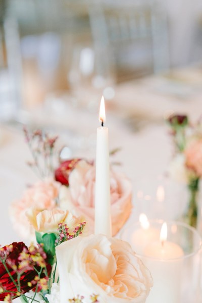 up close shot of candle lit on table with flowers