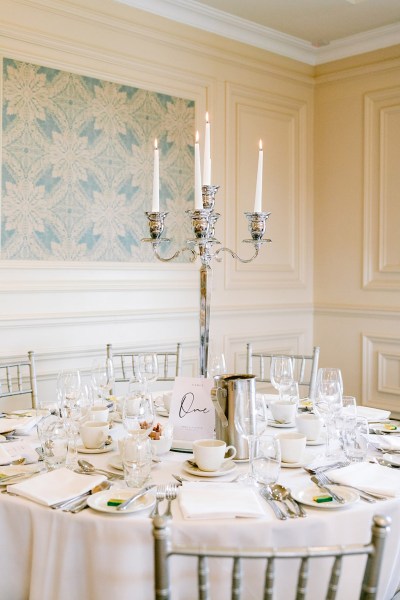 cake beside the long framed window cutlery on tables dining room candles flowers candelabra