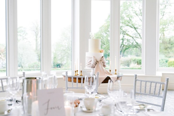 cake beside the long framed window cutlery on tables dining room candles flowers