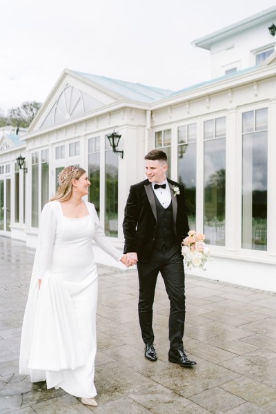 bride and groom walk holding hands outside of venue conservatory