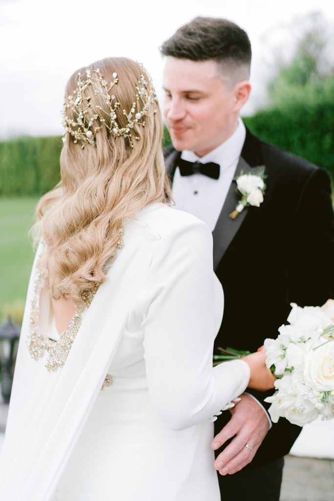 groom looks at his bride she is from behind wavy blonde hair