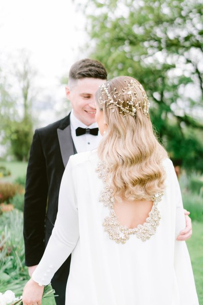 groom looks at his bride she is from behind wavy blonde hair