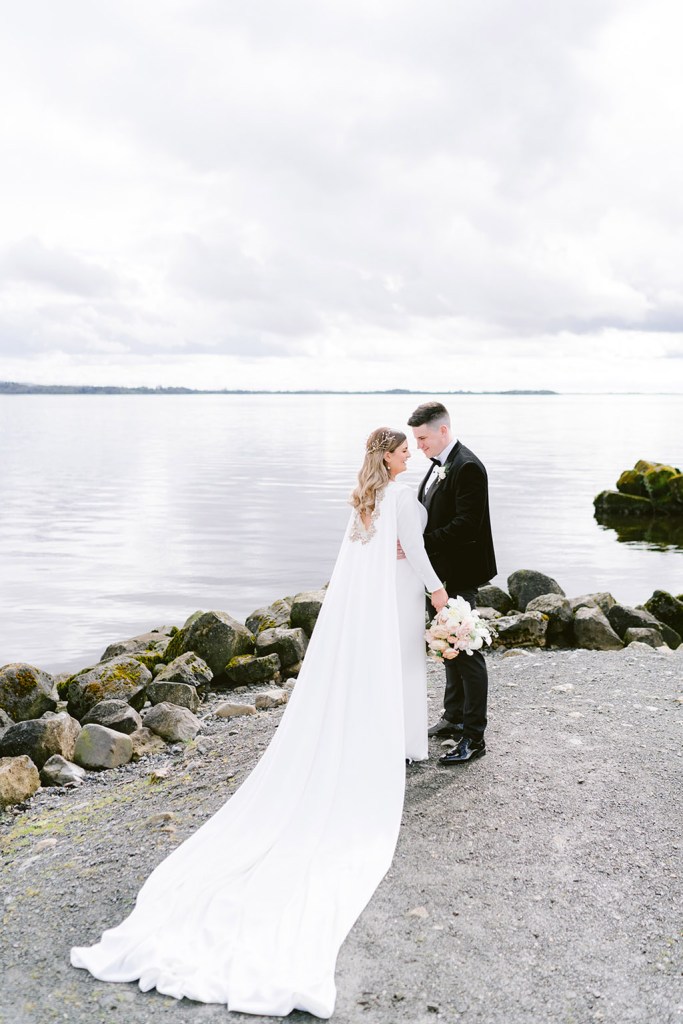 bride and groom face each other sea ocean in background