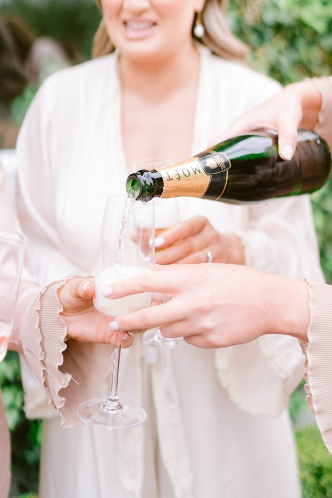 bridesmaid pours champagne into glass