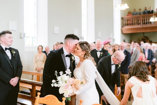 father hands daughter over to groom as he kisses her on the cheek