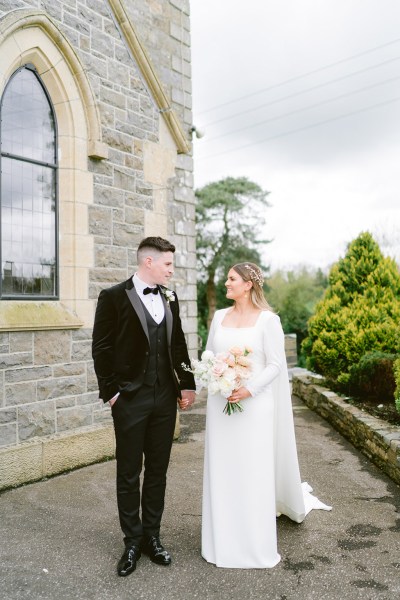 bride and groom look at each other in courtyard to church