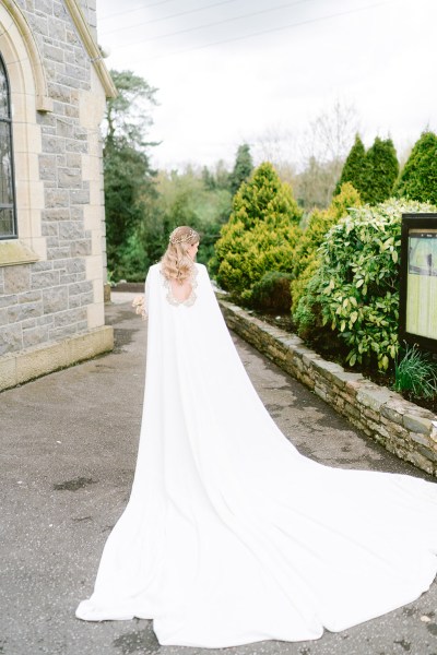 bride in the courtyard to chapel church holding bouquet from behind