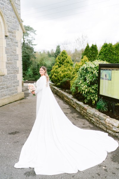 bride in the courtyard to chapel church holding bouquet