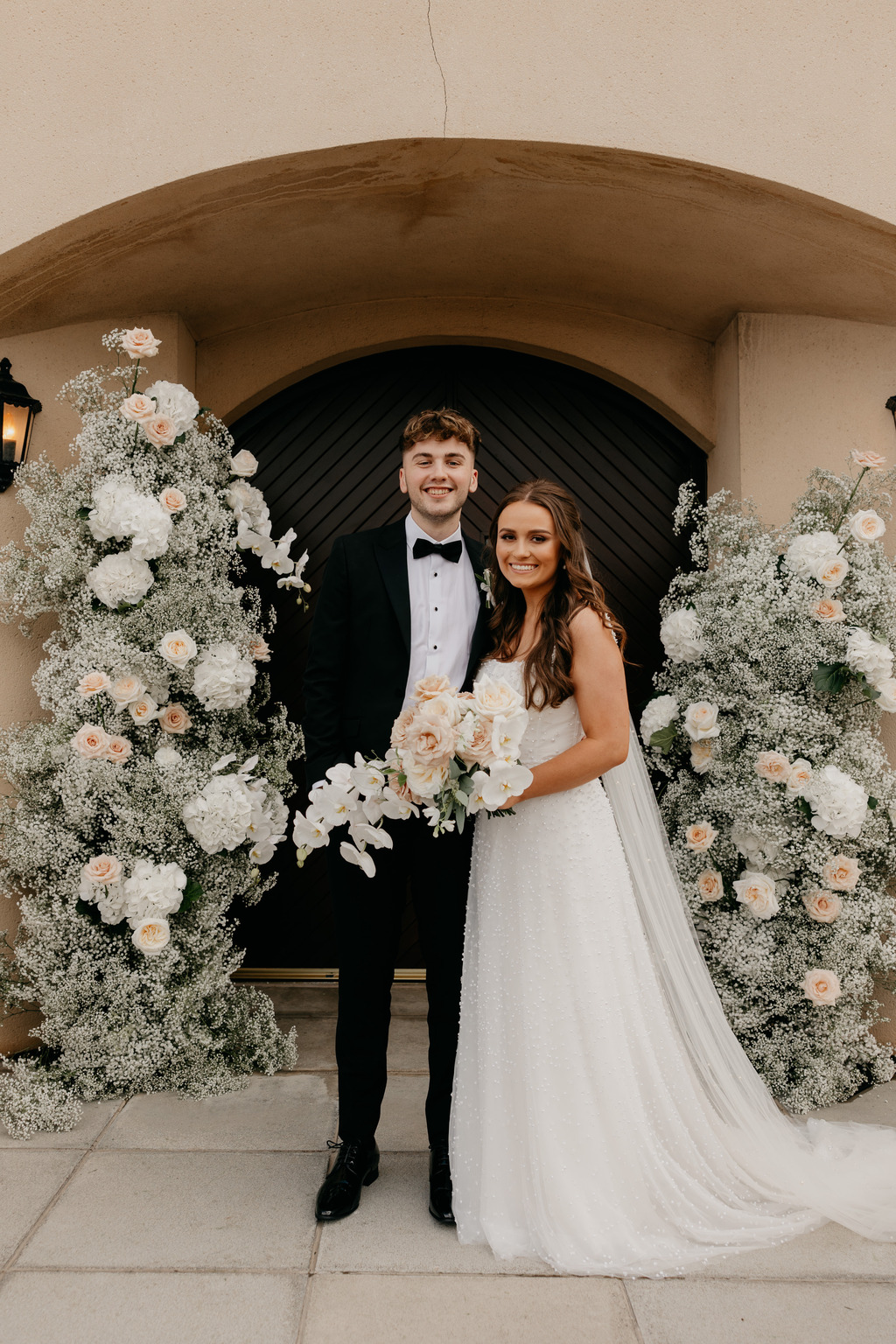 bride and groom stand on the steps outside of church smiling