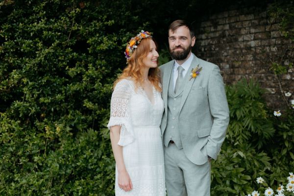 bride and groom stand beside each other in garden