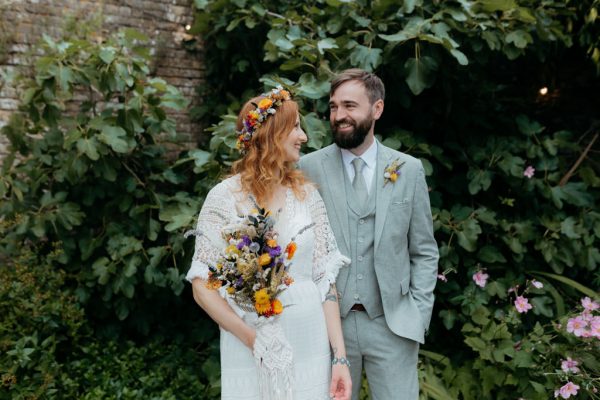 bride and groom standing in the garden she holds bouquet