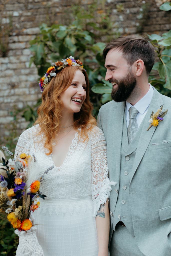 bride and groom standing in the garden she holds bouquet