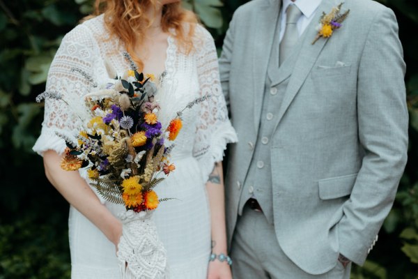 bride and groom standing in the garden she holds bouquet close up