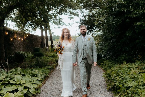 bride and groom walk on pathway to forest setting