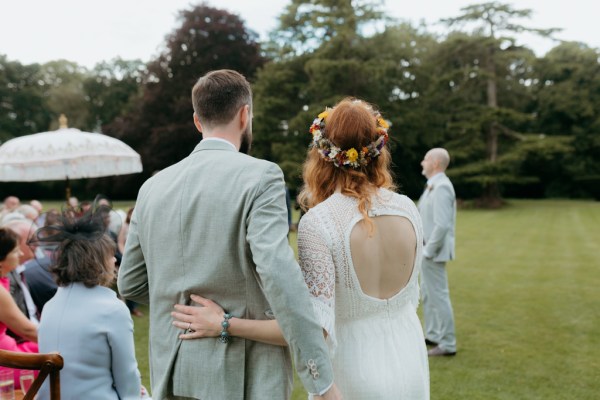 bride and groom from behind grass garden setting and guests