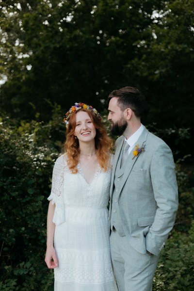 bride and groom walk on the pathway to forest together holding hands she looks at him