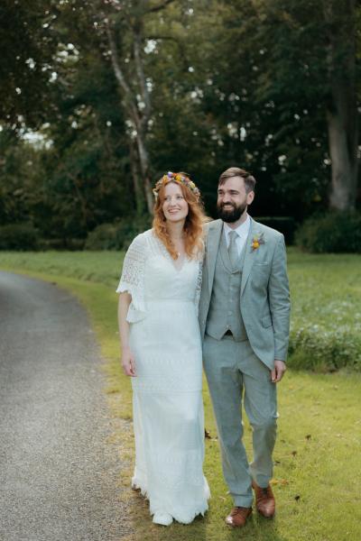 bride and groom walk on the pathway to forest together holding hands and embracing hugging