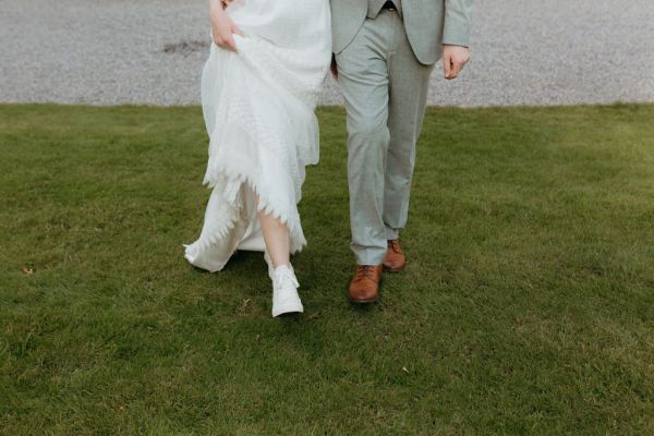 bride and groom walk on the green grass together