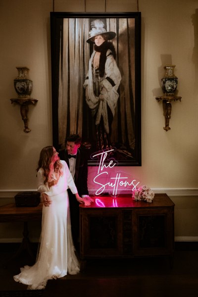 The Suttons pink sign and bride and groom smiling looking at each other