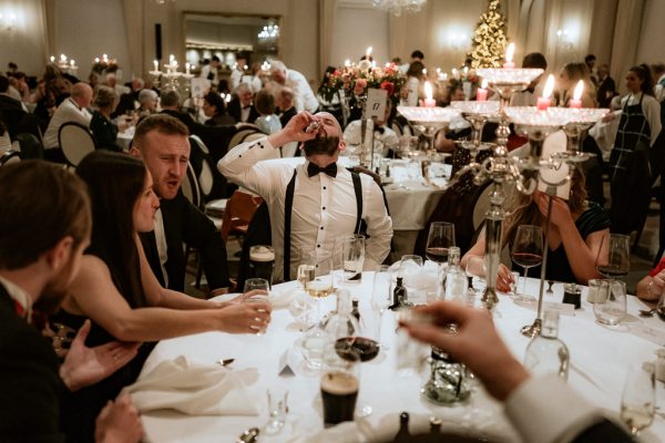 guests seated at table cheers with red wine