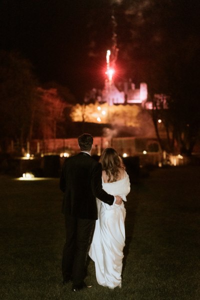 bride and groom looking at fireworks in the distance