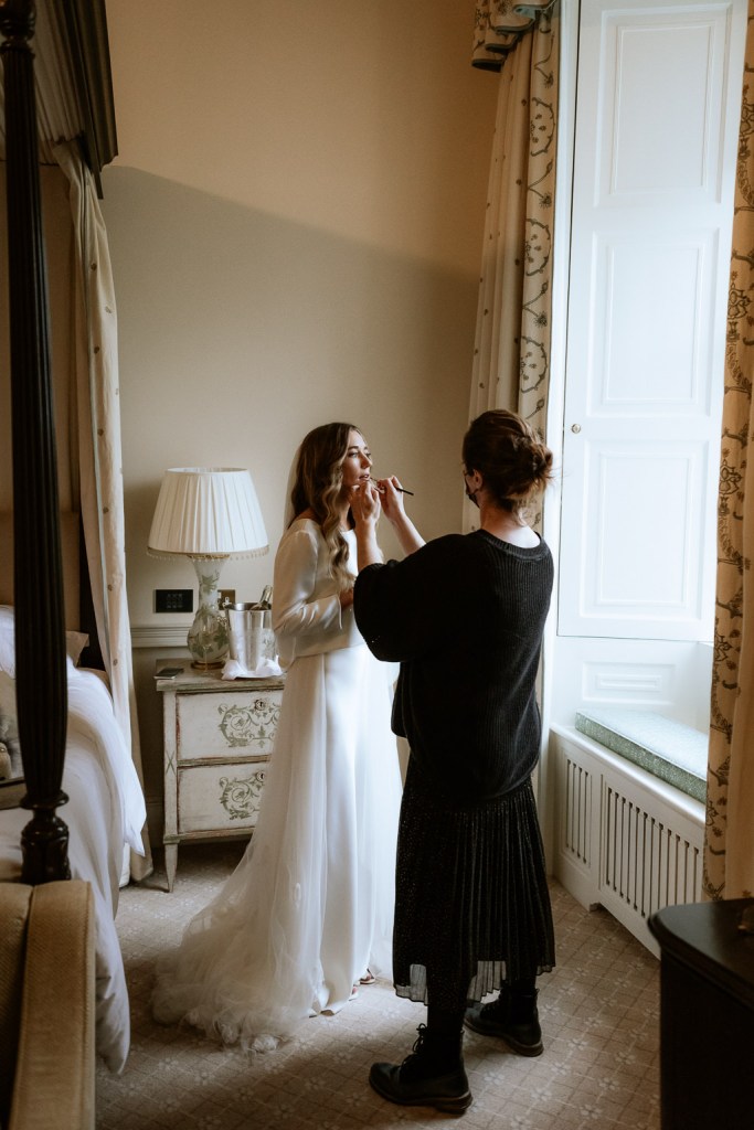 bride getting her makeup done MUA at window