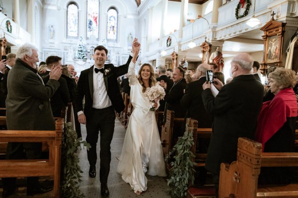 bride and groom hands in the air guests surround them as they clap