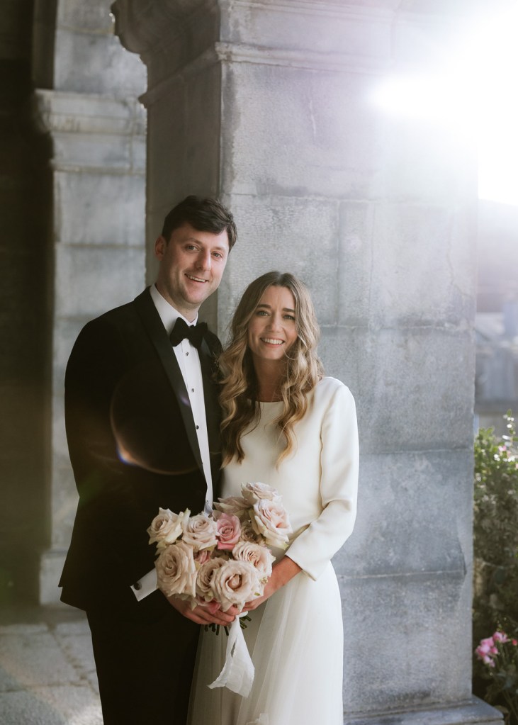 bride and groom smile other as she holds bouquet