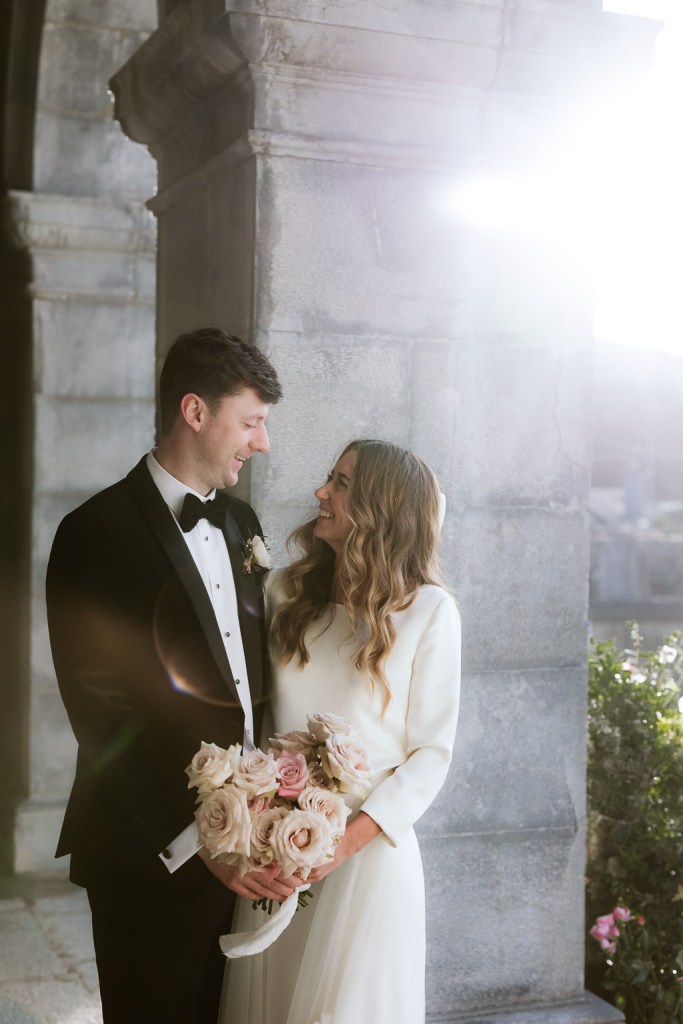 bride and groom look at each other as she holds bouquet