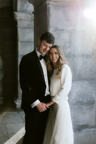 bride and groom hold hands touching heads smiling