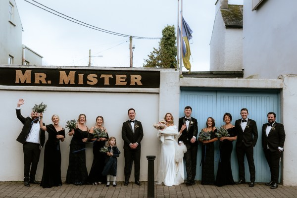 Mr. Mister sign bride groom groomsmen and bridesmaids all have bouquet in the air celebrating