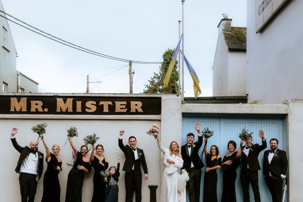 Mr. Mister sign bride groom groomsmen and bridesmaids all have bouquet in the air celebrating