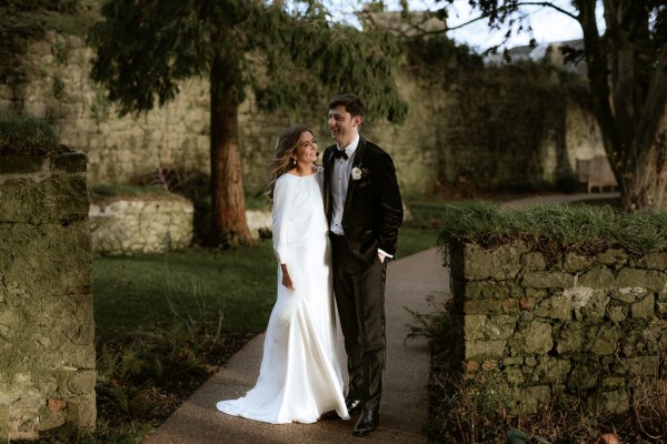 bride and groom stand in park garden together trees in background