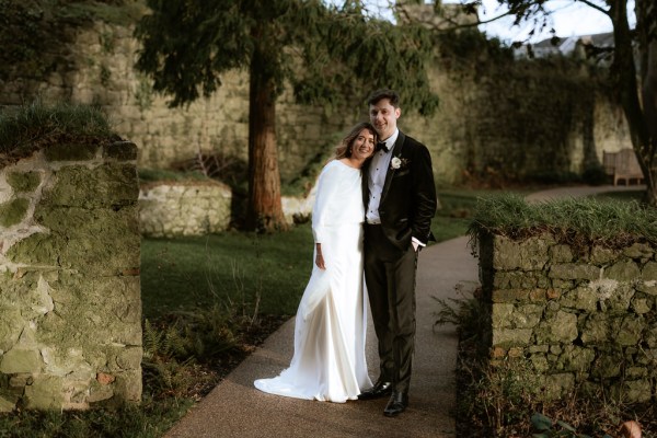 bride and groom stand on the pathway to garden together