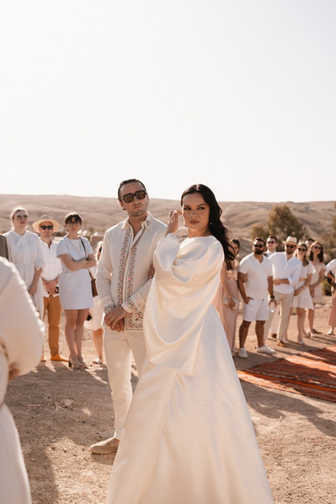 bride and groom stand together in front of guests