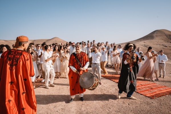 drummer in the middle playing drums guests dance and walk on sand