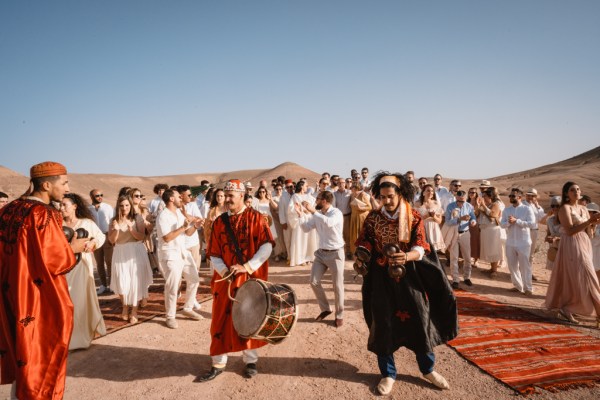 drummer in the middle playing drums guests dance and walk on sand