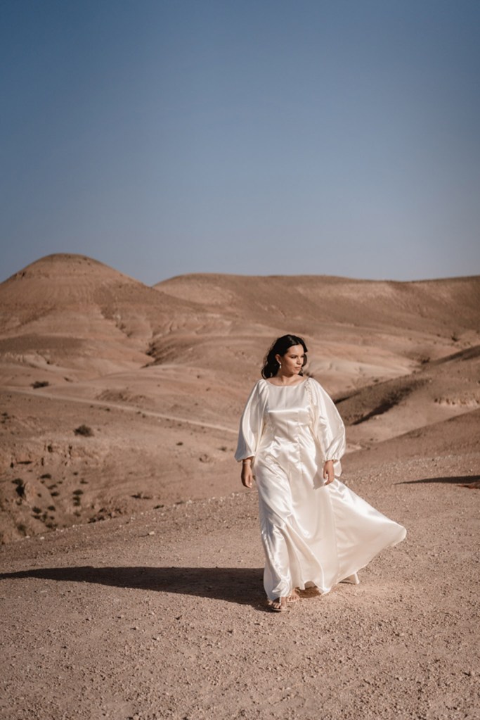 bride walking on the sand dress blowing in the wind