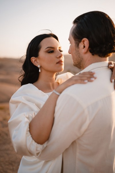 bride holds grooms shoulders she looks at him