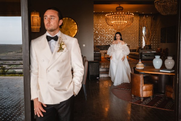 bride approaches groom who stands outside at entrance door