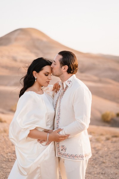 bride and groom kiss in the desert setting mountains in background