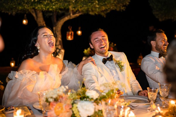 bride and groom sit at the dining room table together laughing