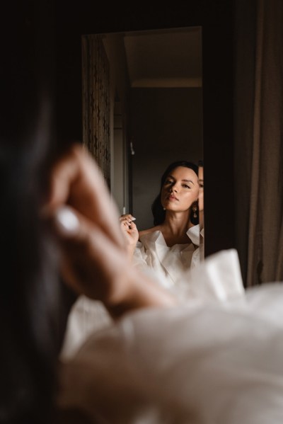 bride sees herself in the mirror reflection getting ready