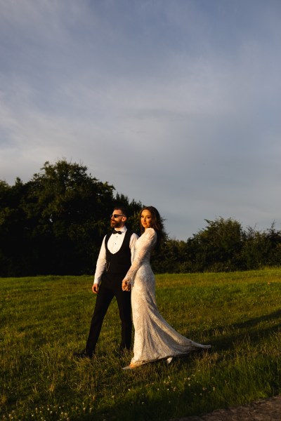 bride and groom walk on the grass scenery in background forest