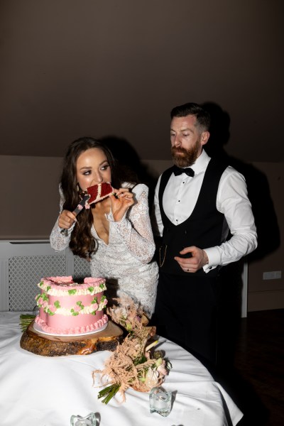 bride and groom eat the pink white frosting wedding cake