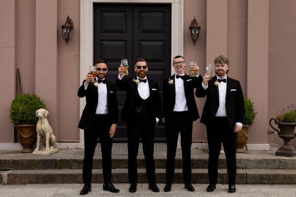 groom and groomsman cheers with pint of beer