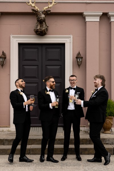 groom and groomsman cheers with pint of beer