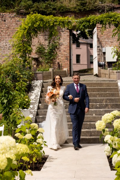 father of the bride walks down the aisle down the steps towards ceremony