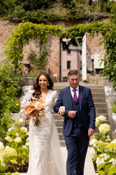 father of the bride walks down the aisle down the steps towards ceremony